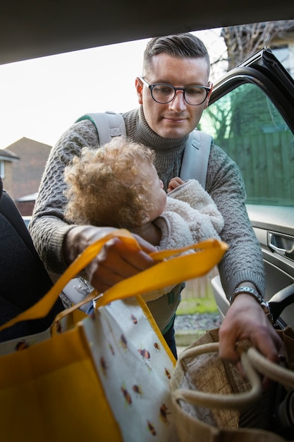 Front view father holding baby in carrier