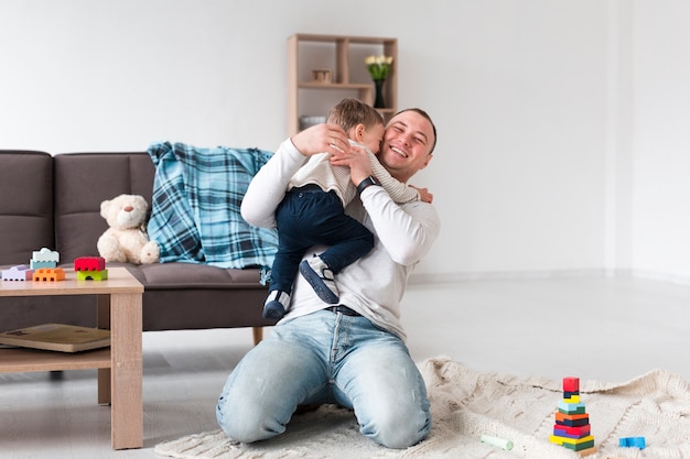 Vista frontale del bambino della tenuta del padre a casa