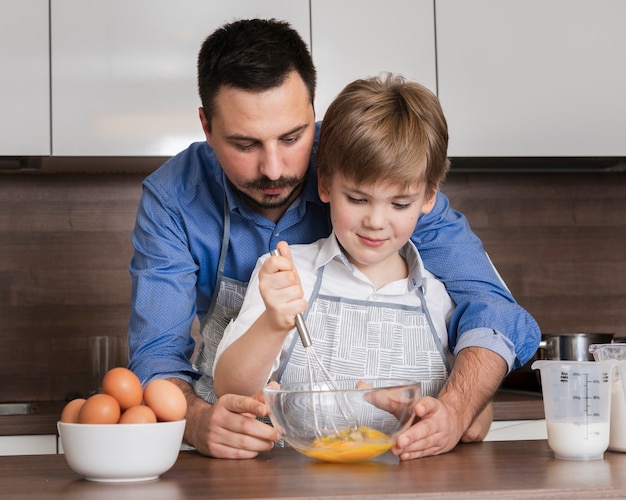 Front view father and son mixing eggs