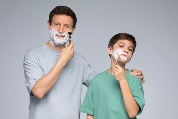 Вид спереди отец учит сына бриться