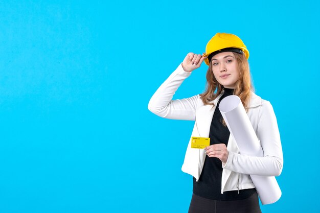 Front view female architect holding bank card on a blue