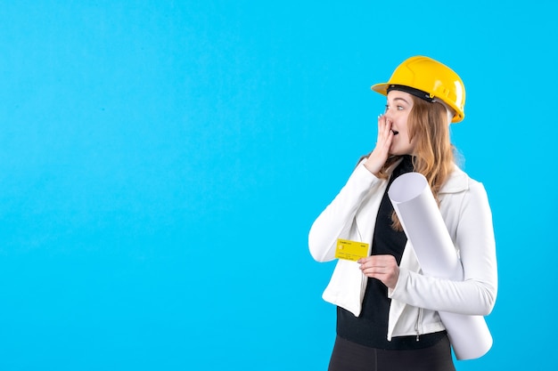 Front view female architect holding bank card on blue