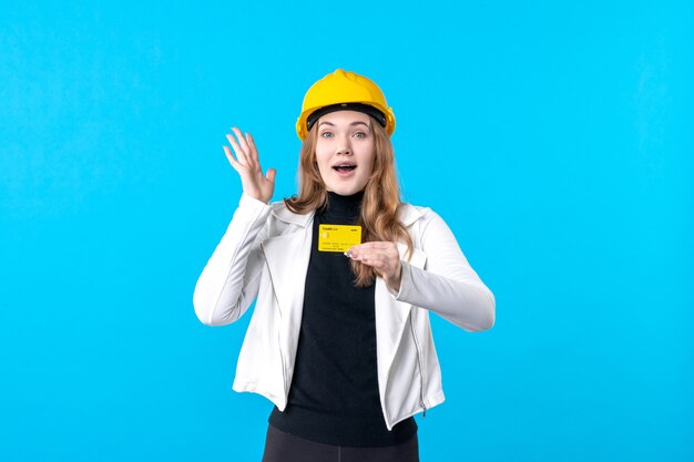 Front view female architect holding bank card on blue