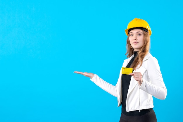 Front view female architect holding bank card on blue