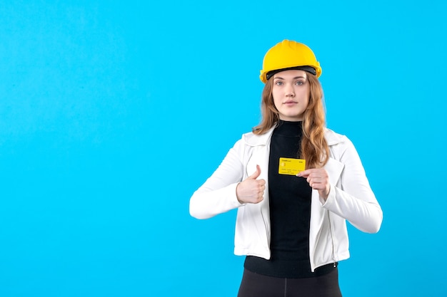 Front view female architect holding bank card on blue