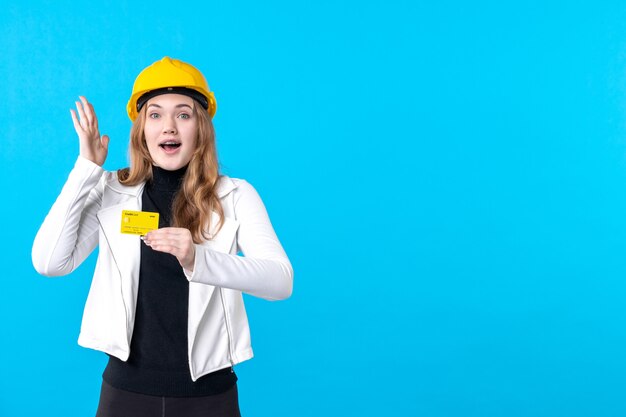 Front view female architect holding bank card on blue