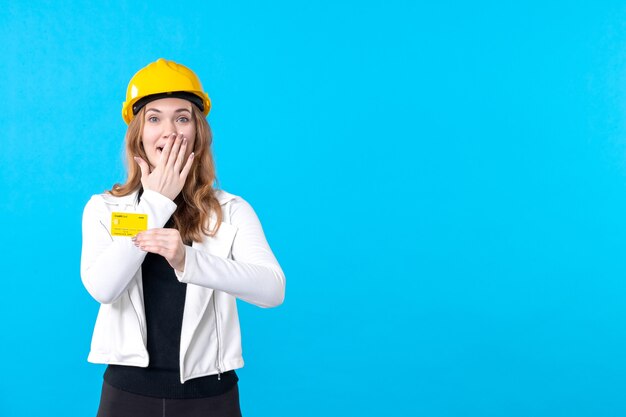 Front view female architect holding bank card on blue