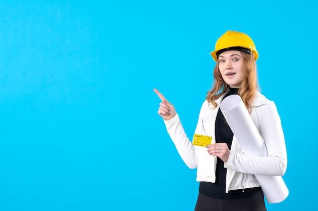 Front view female architect holding plan and bank card on blue