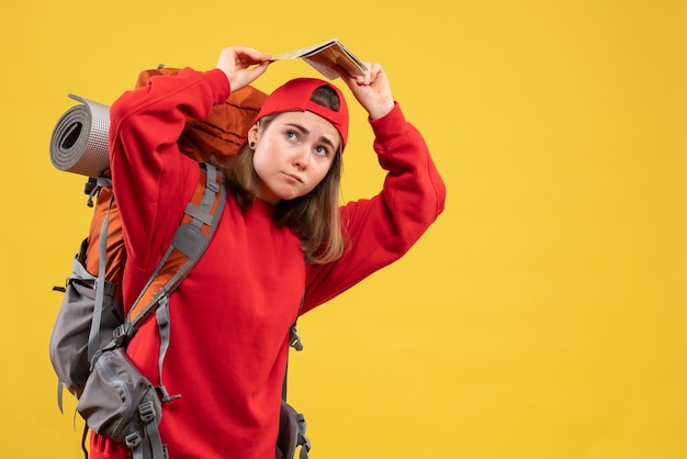 Front view female backpacker holding up travel map over her head