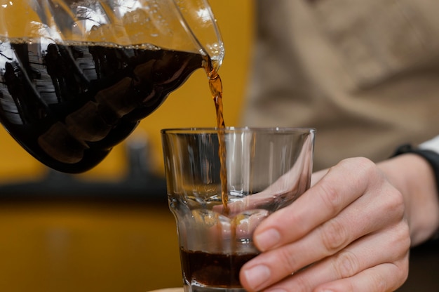 Front view of female barista pouring coffee in transparent glass