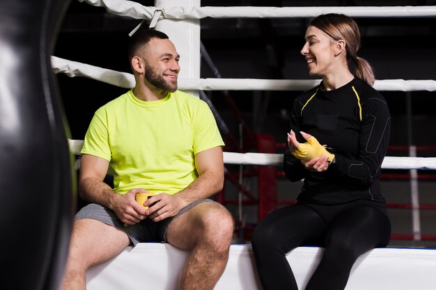 Front view of female boxer chatting with trainer next to ring
