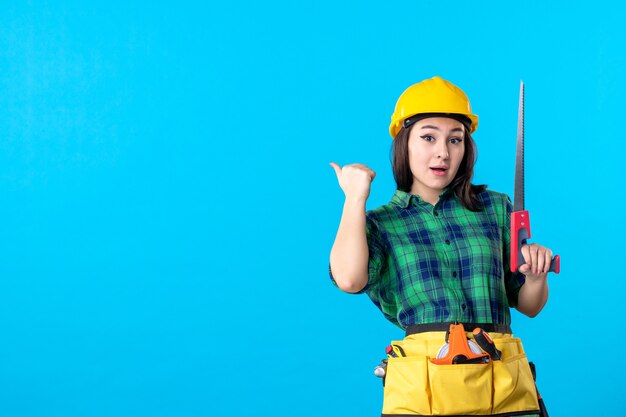 青い仕事の超高層ビルコンストラクター建築労働者に小さなのこぎりを保持している正面図の女性ビルダー