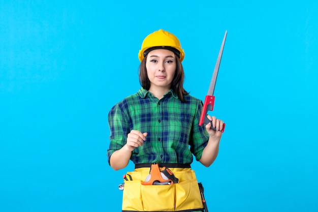 Front view female builder holding little saw on blue