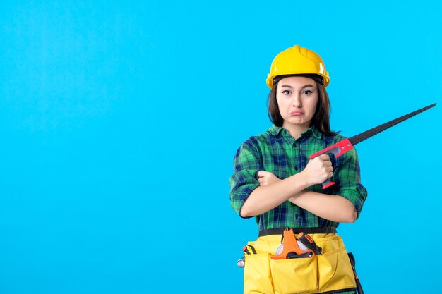 Front view female builder holding little saw on blue