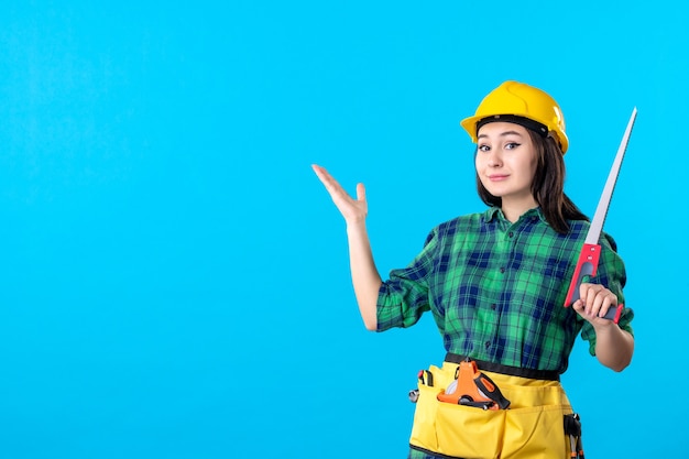 Front view female builder holding little saw on blue