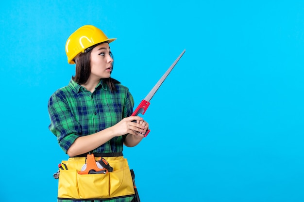 Front view female builder holding little saw on blue