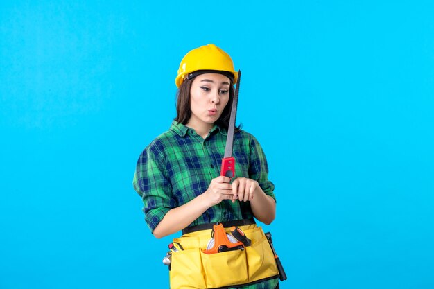 Front view female builder holding little saw on blue