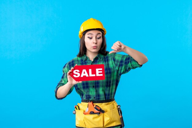 Front view female builder holding red sale writing on a blue