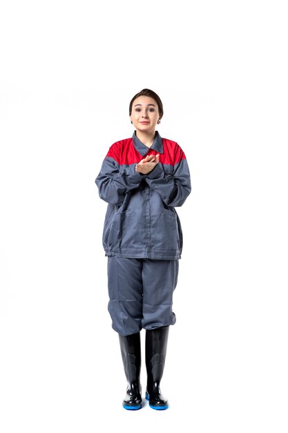 front view of female builder in special uniform clapping on white wall