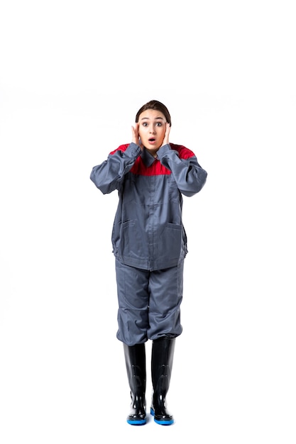 Vista frontale del costruttore femminile in uniforme speciale sul muro bianco