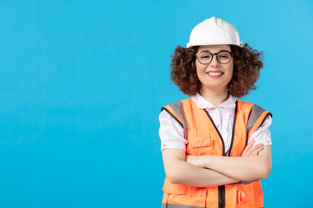 Front view of female builder in uniform on blue wall
