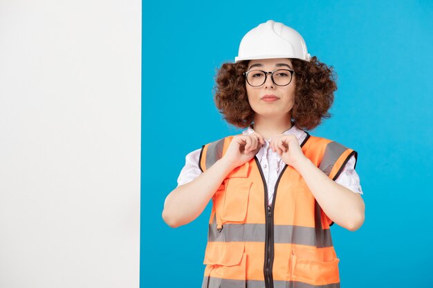 Front view female builder in uniform on blue 