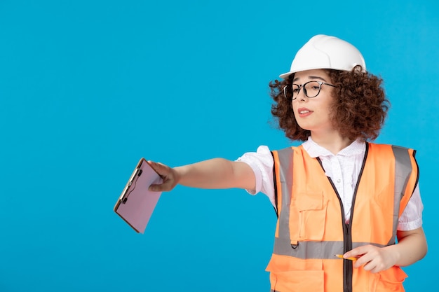 Front view female builder in uniform controlling work on blue 