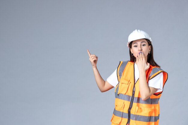 Free photo front view of female builder in uniform on gray wall