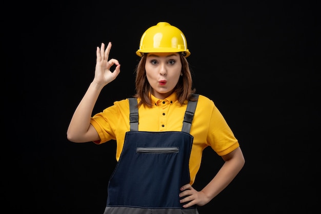 Costruttore femminile vista frontale in uniforme e casco sul muro nero