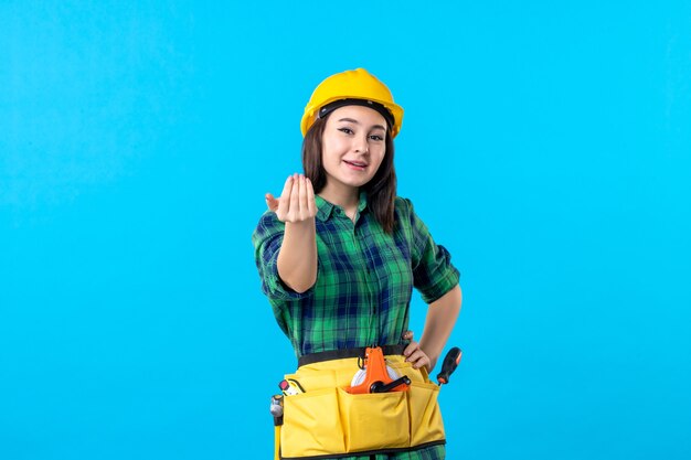 Front view female builder in uniform and helmet on a blue
