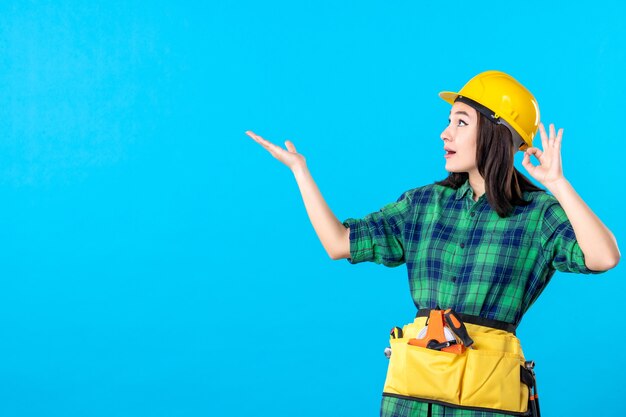 Front view female builder in uniform and helmet on a blue