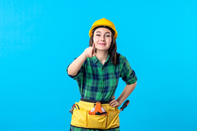 Вид спереди женщина-строитель в униформе и шлеме на синем