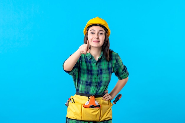 Front view female builder in uniform and helmet on blue