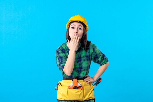 Front view female builder in uniform and helmet on blue