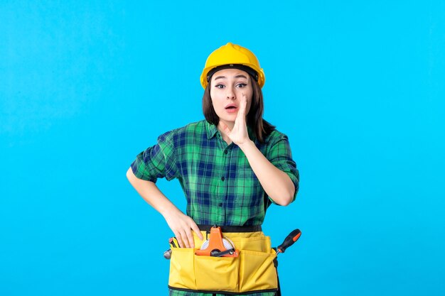 Front view female builder in uniform and helmet on blue