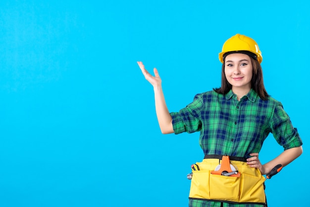 Front view female builder in uniform and helmet on blue