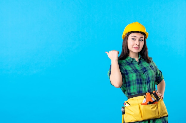 Вид спереди женщина-строитель в униформе и шлеме на синем