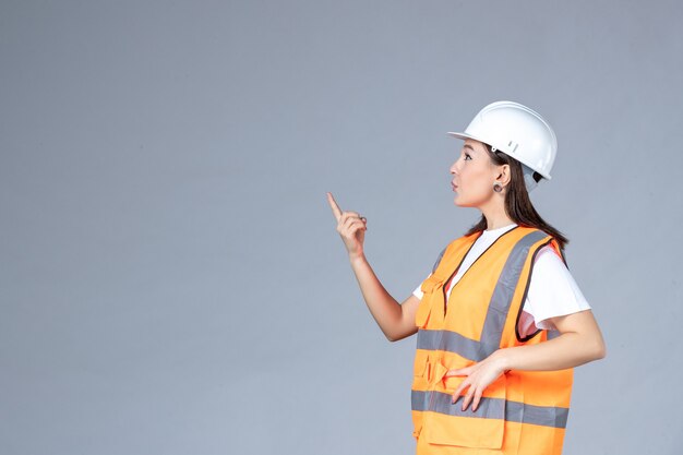 Front view of female builder in uniform on white wall