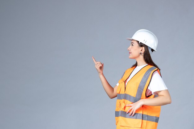 Vista frontale del costruttore femminile in uniforme sul muro bianco