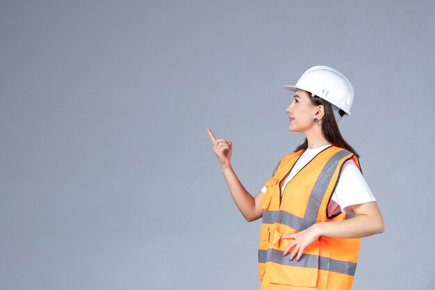 Front view of female builder in uniform on white wall