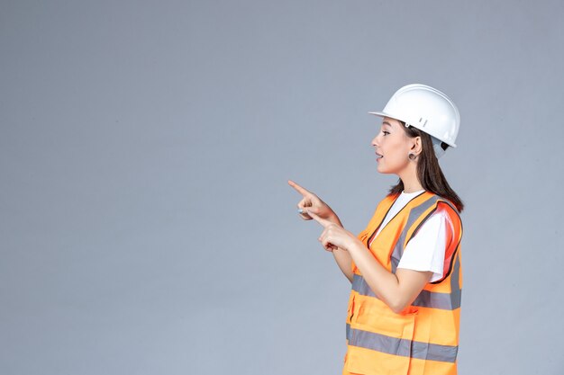 Front view of female builder in uniform on white wall