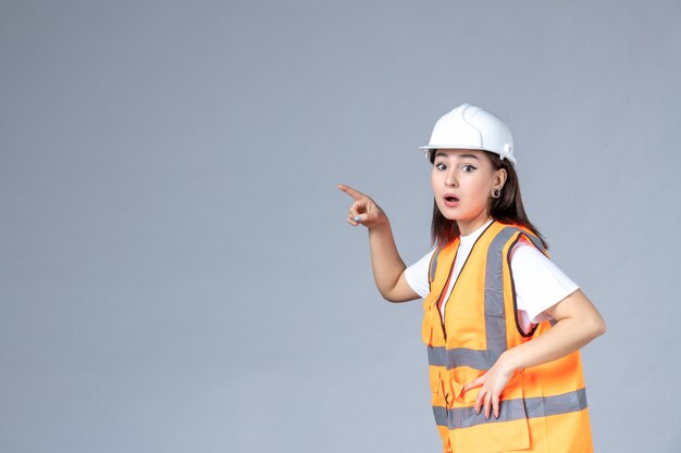 Front view of female builder in uniform on white wall