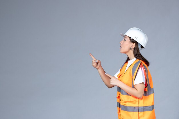 Front view of female builder in uniform on white wall