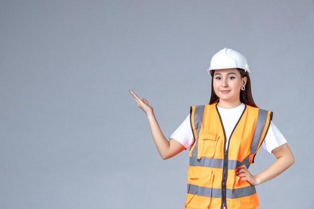 Вид спереди женщины-строителя в униформе на белой стене