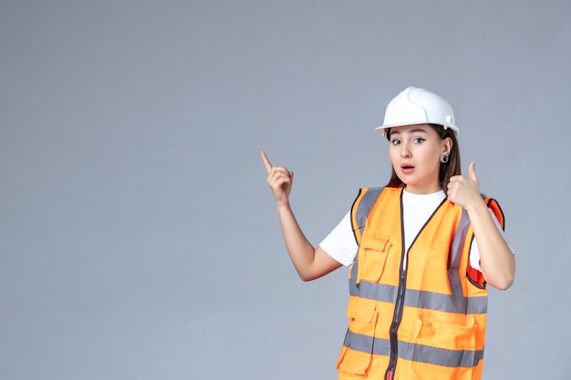 Vista frontale del costruttore femminile in uniforme sul muro bianco