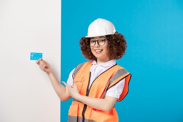 Front view female builder in uniform with blue credit card on blue 