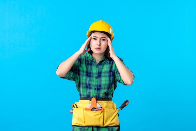 Вид спереди женщина-строитель в униформе с различными инструментами на синем