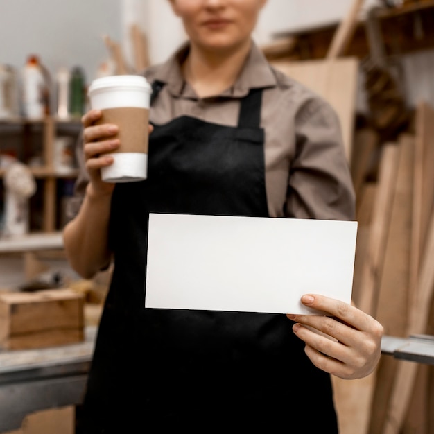 Front view of female carpenter holding coffee and paper