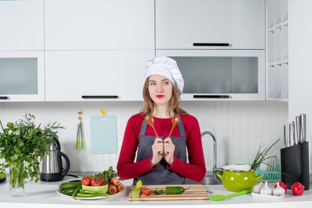 Front view female chef in apron holding spoons