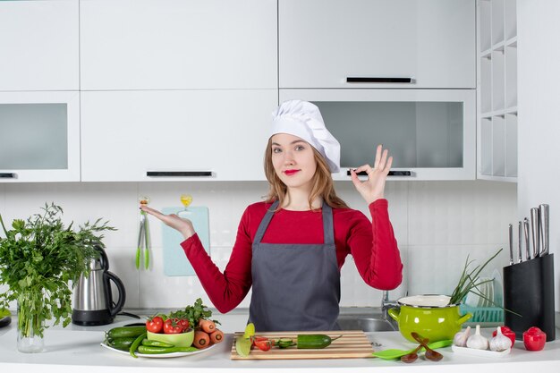 Front view female chef in apron making okey sign